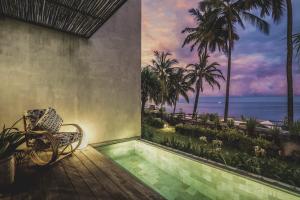 a room with a chair and a view of the ocean at The Tiing Tejakula Villas in Tejakula