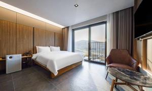 um quarto com uma cama, uma cadeira e uma janela em Anseong Nomad Hotel em Anseong