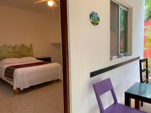 um quarto com uma cama e uma cadeira roxa em Villa Tortugas em Akumal