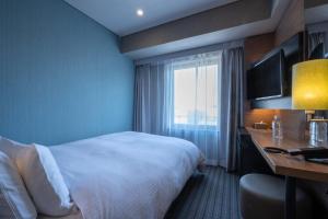 a hotel room with a bed and a desk and a window at Prince Smart Inn Osaka Yodoyabashi in Osaka