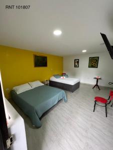a bedroom with two beds and a red chair at El Bambu in Santa Rosa de Cabal