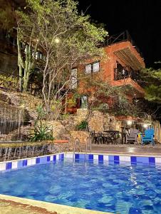 a swimming pool in front of a house at night at Akela Gaira Hotel in Santa Marta