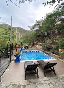 una piscina con 2 sillas y una mesa en Akela Gaira Hotel, en Santa Marta