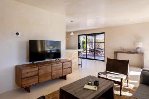uma sala de estar com uma televisão, um sofá e uma mesa em Dt Jt Hot Tub Fire Pit Resort Feels em Joshua Tree