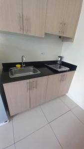 a kitchen with two sinks and a black counter top at SMDC Breeze Residences in Manila