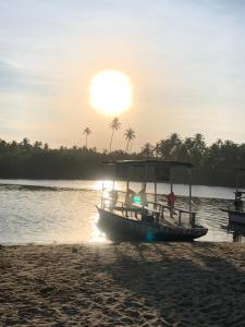 a boat sitting on a beach with the sun setting at Imbassaí Solaris Ap Beach in Imbassai