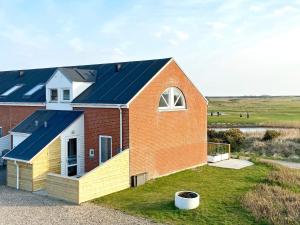 une maison en briques rouges avec un toit bleu dans l'établissement 5 person holiday home in R m, à Rømø Kirkeby