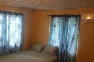 a bedroom with blue curtains and a bed with aermott at Spacious Home in Couva