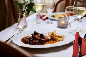 a plate of food on a table with wine glasses at Hotel Lovran in Lovran