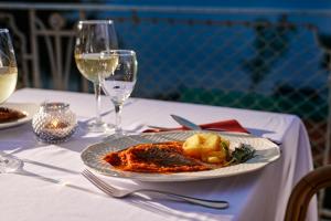 a plate of food on a table with wine glasses at Hotel Lovran in Lovran