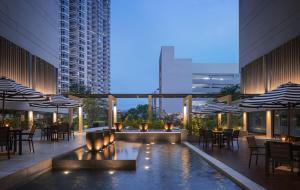 eine Hotelterrasse mit einem Pool, Tischen und Sonnenschirmen in der Unterkunft G Hotel Gurney in George Town