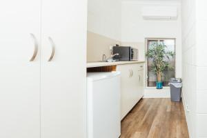 a kitchen with white cabinets and a window at Billabong Lodge Motel in Townsville