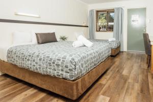 a bedroom with two beds and a wooden floor at Billabong Lodge Motel in Townsville