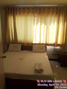 a bedroom with a bed with a window and two shoes at WJV INN LAHUG in Tabok
