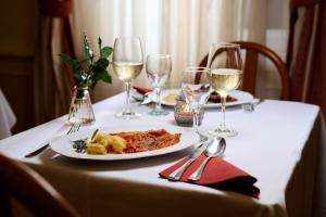 a table with a plate of food and wine glasses at Hotel Lovran in Lovran