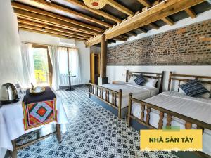 a bedroom with two beds and a brick wall at Wonder Farm Ba Vi - Heritage Retreat in Hà Lộc