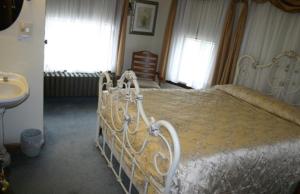 1 cama blanca en un dormitorio con lavamanos en Tarry Here Mansion Bed & Breakfast, en Salamanca