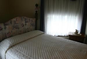 a bedroom with a bed with a white comforter and a window at Tarry Here Mansion Bed & Breakfast in Salamanca +1 photo