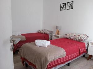 een slaapkamer met 2 bedden met rode lakens en een tafel bij Hotel Lobo de Mar - Las Heras in Mar del Plata