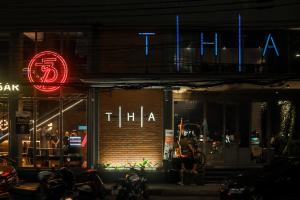 THA City Loft by TH District في بانكوك: يوجد متجر أمامه علامة نيون في الليل