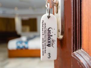een label hangend aan een deur met een bed op de achtergrond bij Hotel Galaxy Opp Surat Railway Station in Surat