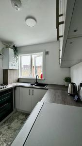 eine weiße Küche mit einem Waschbecken und einem Fenster in der Unterkunft Cozy home in a peaceful area in Hayes