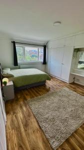 Schlafzimmer mit einem Bett, einem Fenster und einem Teppich in der Unterkunft Cozy home in a peaceful area in Hayes