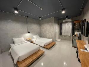 a bedroom with two beds and a television in it at Loft Space Hotel in Ranong