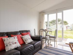 a living room with a black leather couch and a table at 171 Atlantic Bays in Padstow