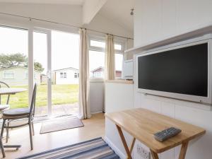 a living room with a flat screen tv and a table at 171 Atlantic Bays in Padstow