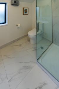a bathroom with a glass shower and a toilet at Explore Addington and CBD 1 bed w/carpark in Christchurch