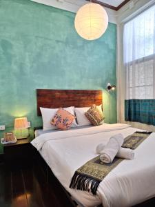 1 dormitorio con 2 camas y pared verde en Thaweesuk Heritage Homestay, en Phang Nga