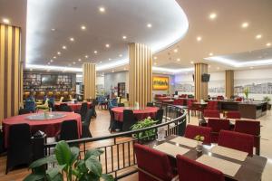 a restaurant with red tables and chairs and aietyietyietyietyumerableumerableumerable at d'primahotel Kualanamu Medan Formerly Prime Plaza Hotel in Medan