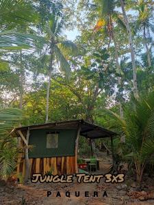 una pequeña cabaña con un cartel delante de algunos árboles en Jungle Tent 3x3, Latino Glamping & Tours, Paquera en Paquera