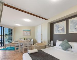 a bedroom with a bed and a bathroom with a tub at La Promenade in Caloundra