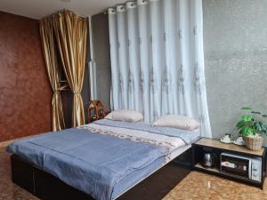 a bedroom with a bed with blue sheets and a curtain at The Greenergy - NO ELEVATOR in Hat Yai
