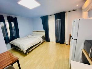 a small room with a bed and a refrigerator at Miru House in Seogwipo