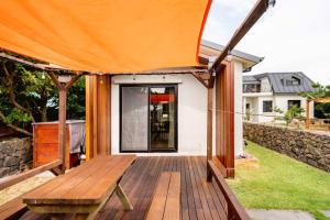 ein Haus mit einer Holzterrasse mit einem orangenen Zelt in der Unterkunft Miru House in Seogwipo