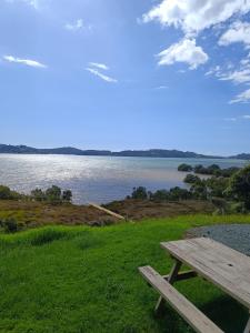 a wooden picnic table sitting on the grass near a lake at Laurels Retreat in Mangonui