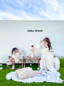 two women are sitting on chairs in the grass at Hotel Imagine Kyoto in Kyoto