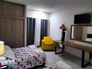 Cette chambre comprend un lit, un bureau et une chaise jaune. dans l'établissement Hotel La Estancia, à Río Verde