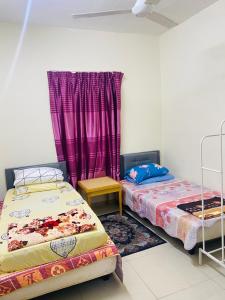 two beds in a room with purple curtains at Homestay Zalida D Musleem in Kampong Alor Gajah