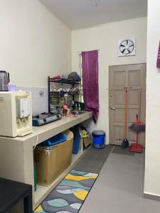 a room with a kitchen with a counter and a microwave at Homestay Zalida D Musleem in Kampong Alor Gajah