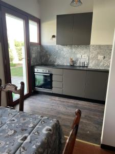 uma cozinha com armários cinzentos, uma mesa e uma janela em Villa Giannella em Orbetello