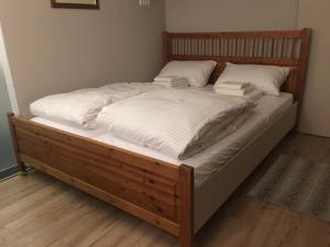 un grande letto in legno con lenzuola e cuscini bianchi di Bialik St B&B room Bauhaus district Tel Aviv a Tel Aviv
