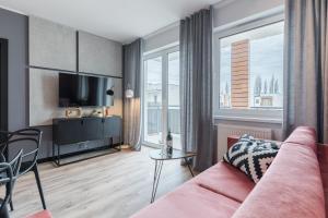 ein Wohnzimmer mit einem rosa Sofa und einem Tisch in der Unterkunft Platinum Premium Apartment in Graudenz