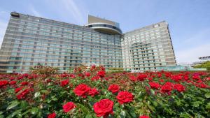 un gran edificio con rosas rojas delante de él en Hotel New Otani Tokyo EXECUTIVE HOUSE ZEN, en Tokio