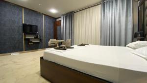 1 dormitorio con 1 cama blanca grande y TV en JINJU, en Yakkasaray