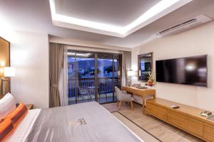 Habitación de hotel con cama, escritorio y TV. en Jomkitti Boutique Hotel en Chiang Mai