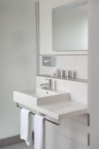 a white bathroom with a sink and a mirror at Hotel Bären Suhr in Aarau